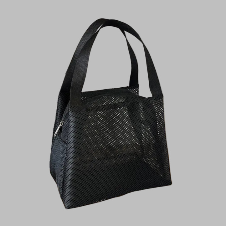 Black mesh handbag on a wooden surface with motivational quote in the background
