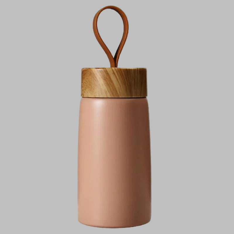 Pink thermos with wooden lid and handle on a white background